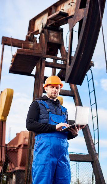 oil-engineer-with-a-laptop-standing-next-to-an-oil-DLZ7RBS.jpg